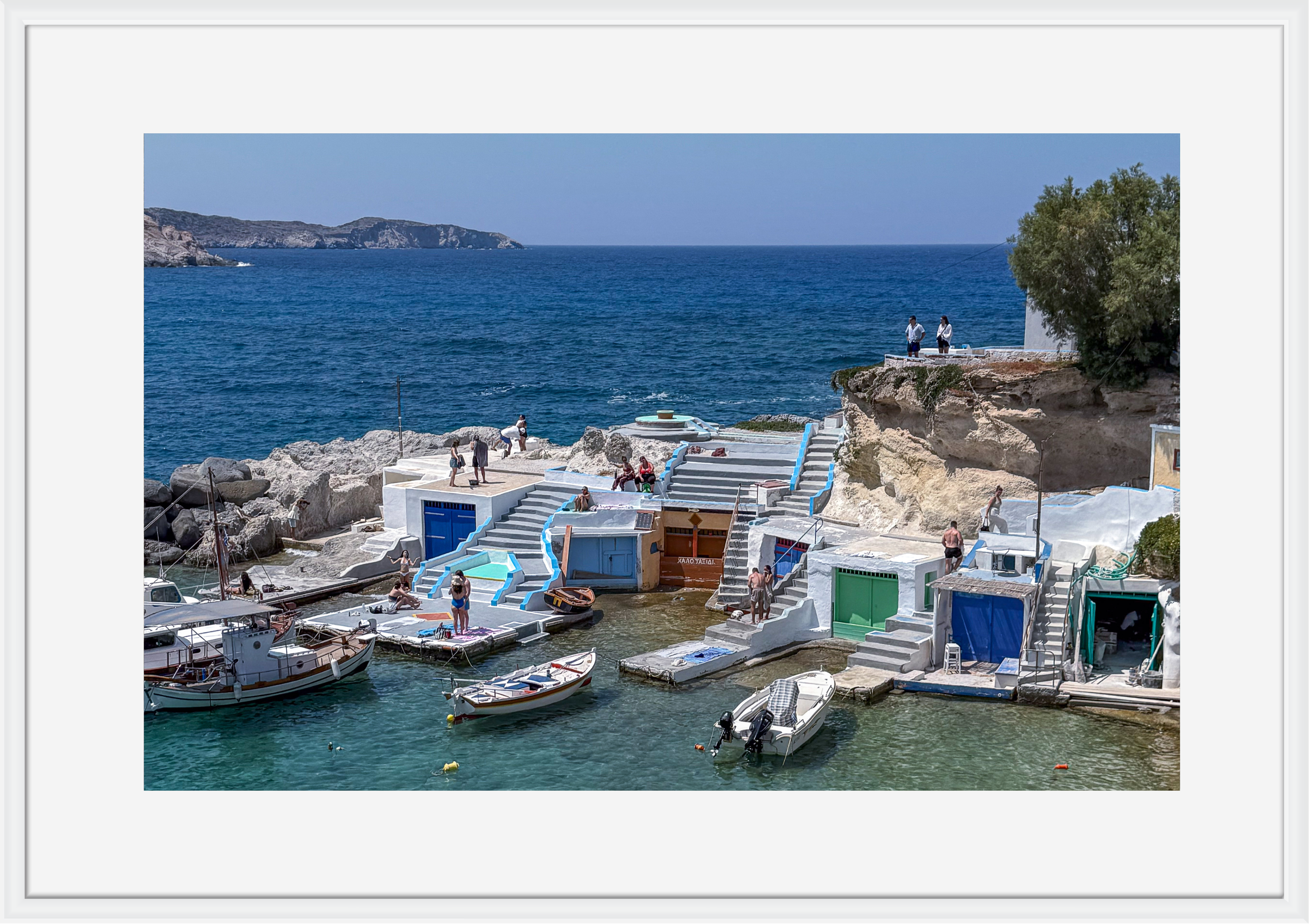 Coastal scene with boats docked near a rocky shore and clear blue sky.