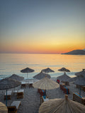 Straw beach umbrellas at dusk in Himare, Albania – photographic wall art print